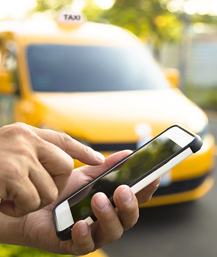Finger tippt auf Smartphone im Hintergrund Taxi